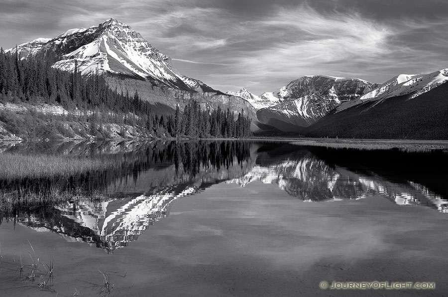 Only a small ripples disturbs the reflection of the mountains in the distance. - Canada Photography
