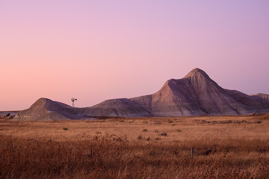 Scenic landscape photograph of a windmill and badlands during dusk in western Nebraska. - Nebraska Photography