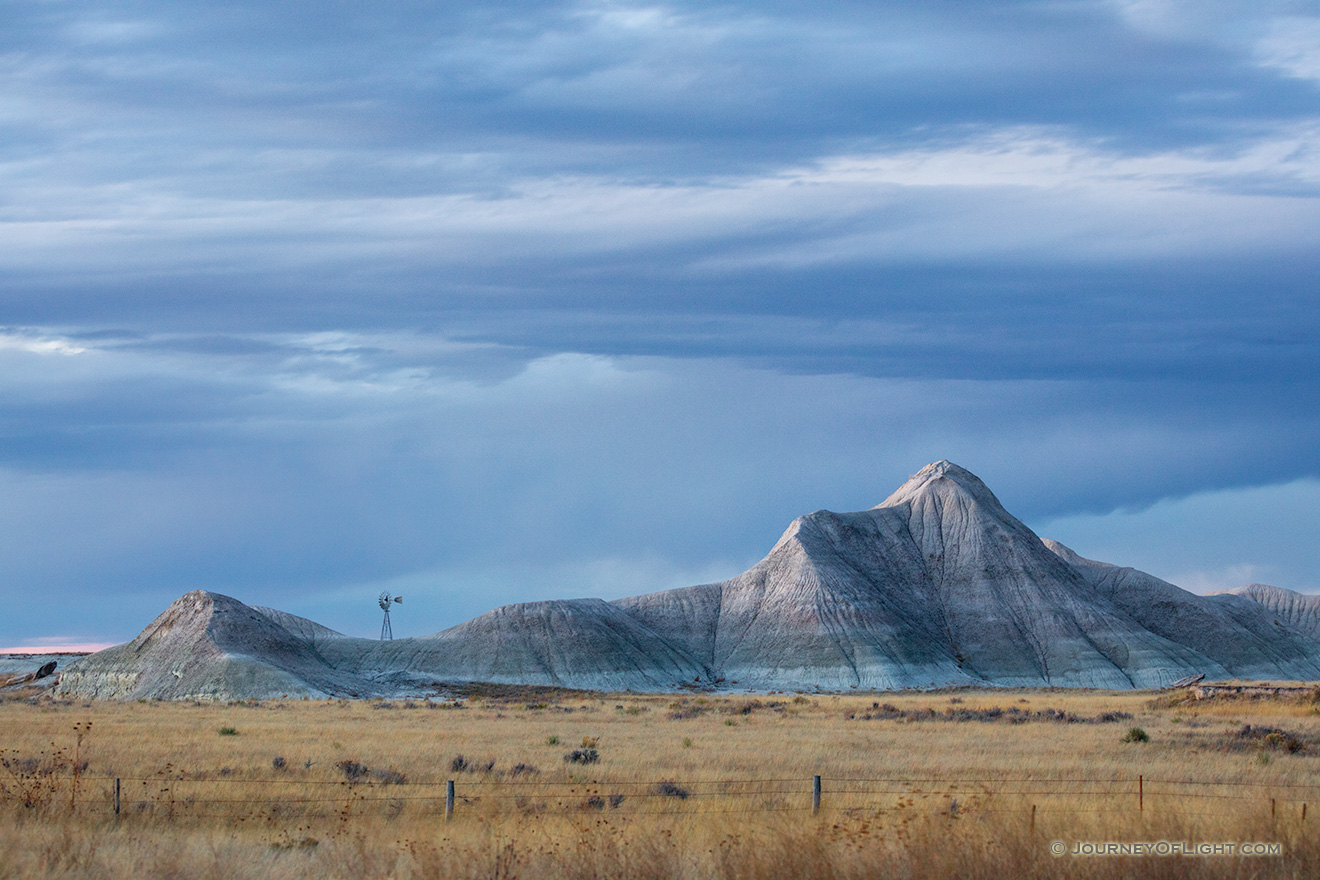 Scenic landscape photograph of a windmill and badlands during dusk in western Nebraska. - Nebraska Picture