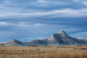 Scenic landscape photograph of a windmill and badlands during dusk in western Nebraska. - Nebraska Photograph