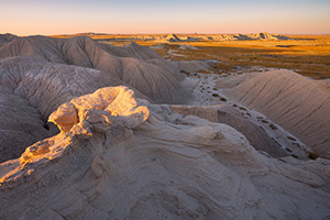 As the sun sets warm sunlight bathes parts of Toadstool Geologic Park in warm hues. - Nebraska Photograph