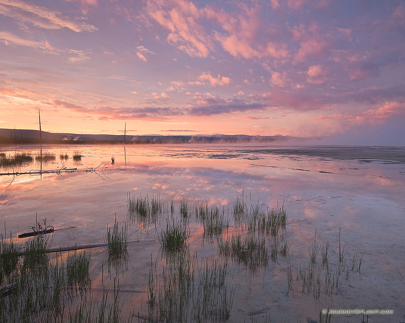 On a quiet evening in Yellowstone National Park I hiked out in the Middle Geyser area and witnessed the still water from the geysers reflected the fiery sunset in all directions.  The sunset albeit brief in the scheme of the day seemed to last longer than usual as the oranges gave way to pinks and then purples.  This was the image from near the end of the drama of sunset. - Yellowstone National Park Picture