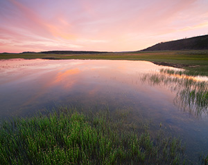 Clouds are illuminated with bright reds and oranges during a vivid sunset in the Hayden Valley of Yellowstone National Park in Wyoming. - Wyoming Landscape Photograph