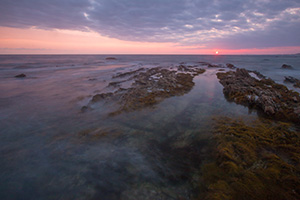 An orange sun sets over the Pacific Ocean at Crystal Cove State Park, California. - California Landscape Photograph