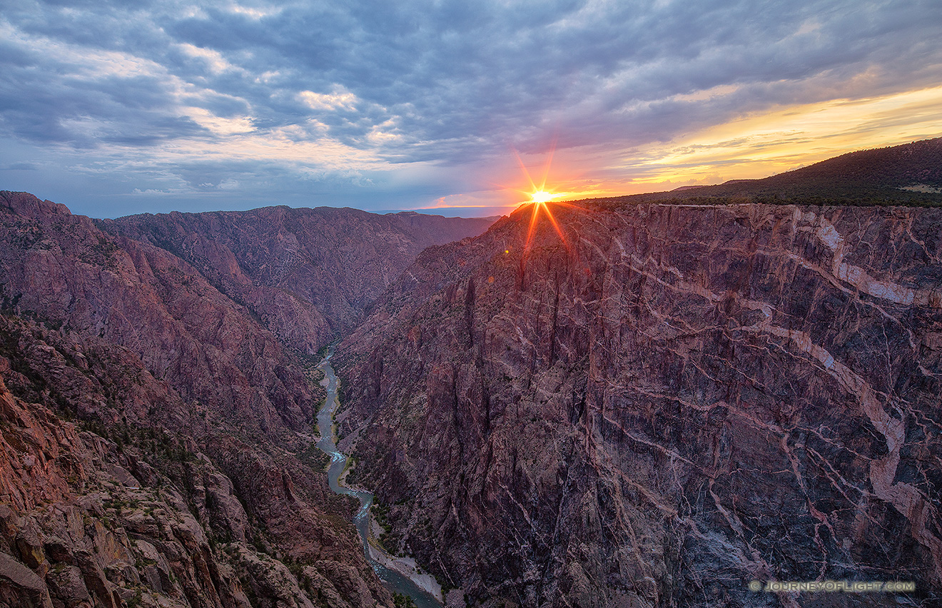 The last bit of sun hangs just above the canyon wall at Black Canyon of the Gunnison National Park on a cool summer evening. - Colorado Picture