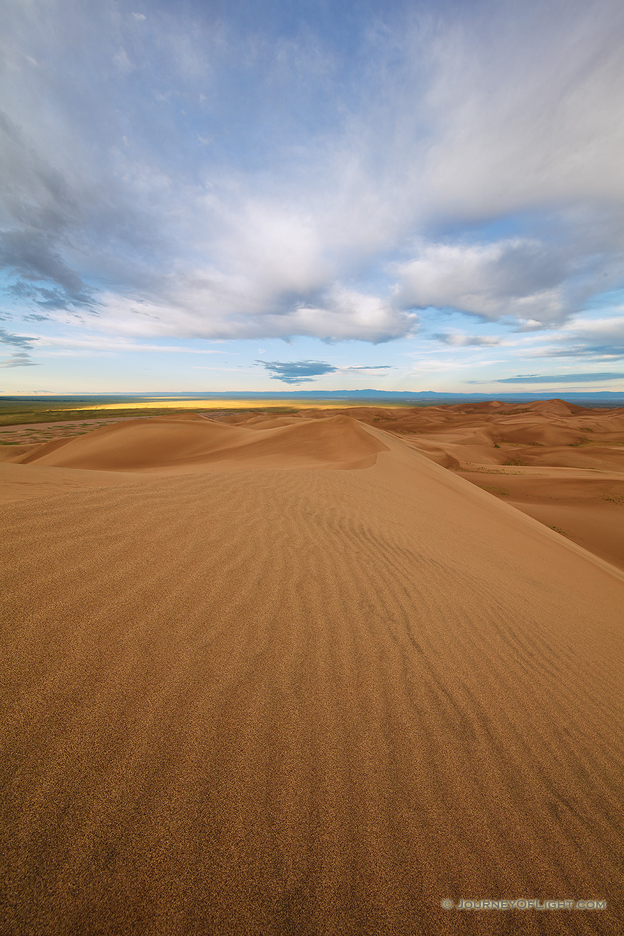 Dunes flow into the west at Great Sand Dunes National Park as white clouds lazily float above. - Great Sand Dunes NP Photography