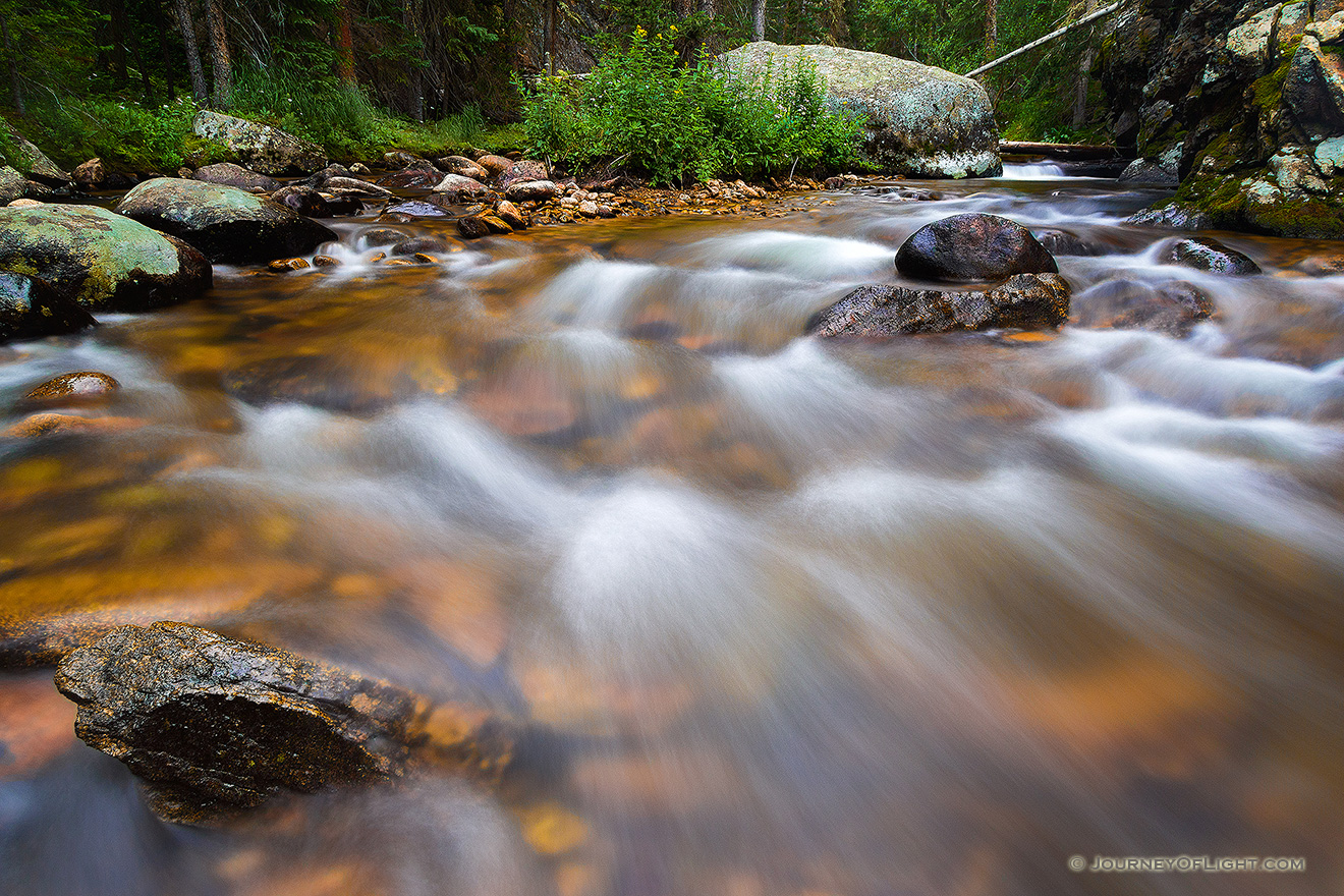 As the North Inlet River flows through the west part of Rocky Mountain National Park, cascading gently over rocks and around the summer wildflowers. - Colorado Picture