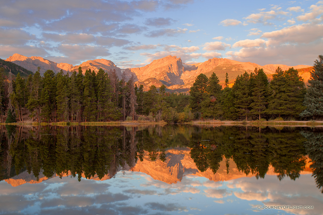 During a cool October sunrise the peaks of the continental divide, Powell Peak, Taylor Peak, Otis Peak, Hallett Peak, and Flattop Mountain are reflected in the calm waters of Sprague lake. - Rocky Mountain NP Picture