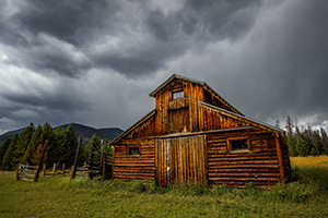 Under stormy clouds, a wooden barn sits in the Kawuneeche Valley on the western side of Rocky Mountain National Park in Colorado. - Colorado Landscape Photograph