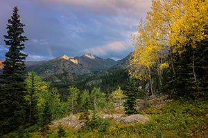 On a cool autumn evening sun strikes the peak of Long's Peak in Rocky Mountain National Park.  A faint rainbow briefly appeared as the storm moved over the mountain. - Colorado Landscape Photograph