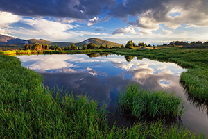 An idyllic mountain scene on the tundra of Rocky Mountain National Park.  A small tarn reflects the beautiful sky and the mountains in the distance. - Colorado Landscape Photograph Photograph