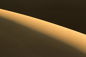 Morning sun streams across Great Sand Dune National Park and Preserve illuminating the tops of the dunes. - Colorado Abstract Photograph