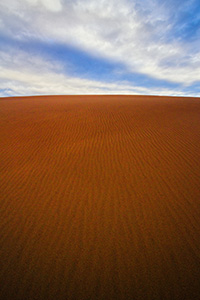 From the base of a tall dune looking skyward, clouds float above the dunes at Great Sand Dune National Park. - Colorado Landscape Photograph Photograph