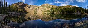 Deep in the backcountry of Rocky Mountain National Park, the mountains surrounding Lake Nokoni, sky and clouds reflect in the clear water. - Colorado Scenic Photograph Photograph