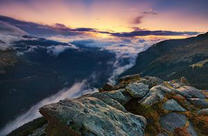 As clouds gather in the valley below, from the tundra of Rocky Mountain National Park, the sun sets behind the mountains of Colorado, the last rays burst forth with orange and yellow before dimming altogether. - Colorado Photograph