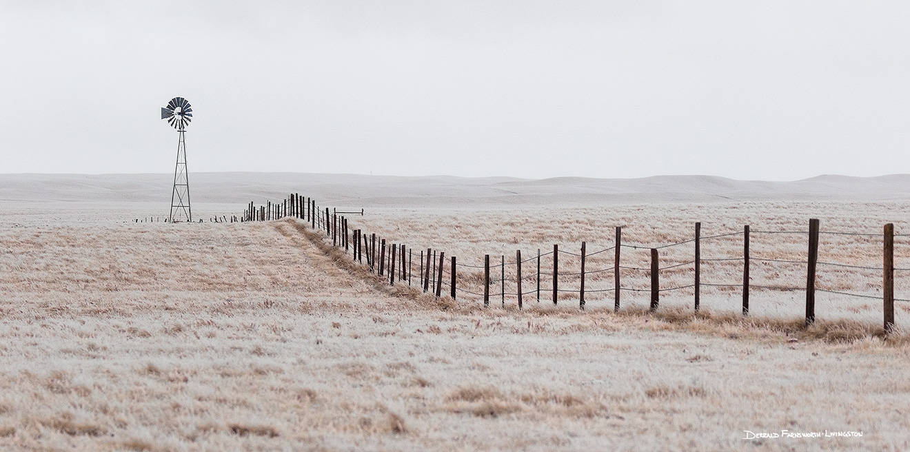 Scenic landscape panoramic photograph of a windmill and a fence in the winter at Oglala National Grasslands. - Nebraska Picture