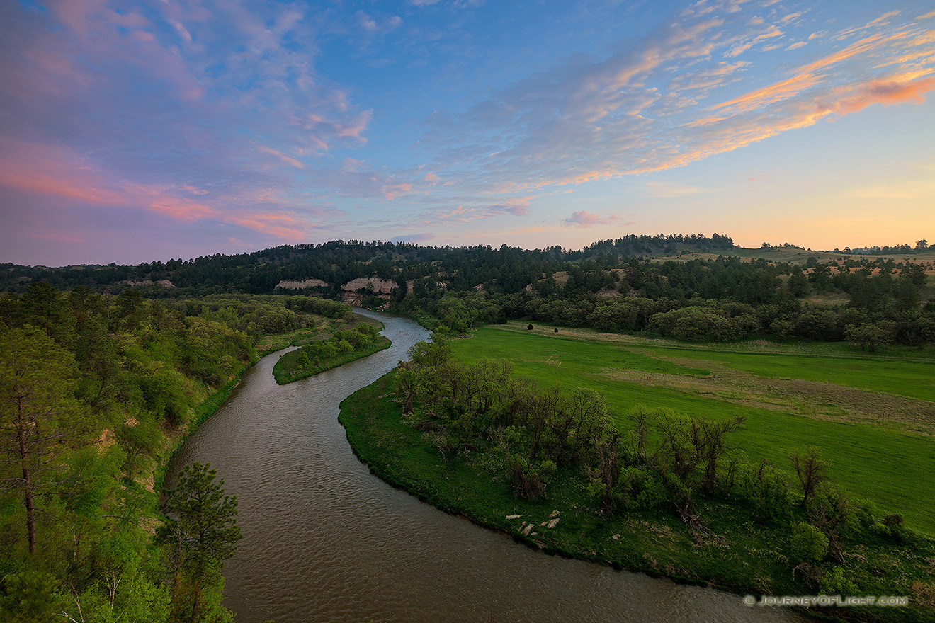 The Niobrara river west of Niobrara National Wildlife Refuge, snakes through a lush green valley on a beautiful spring morning. A cool breeze blew gently as the sun rose in the east illuminating the clouds in the sky. - Valentine Picture