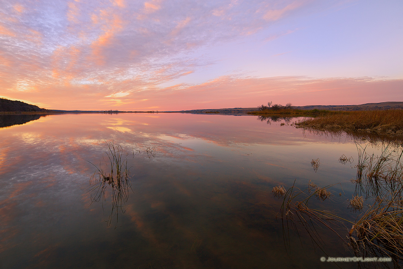 On a calm and quiet evening in early November at Niobrara State Park, just prior to sunset, I hiked down to near the confluence of the Missouri River and Niobrara Rivers and took in the scene.  The last of the light of the sun illuminated the clouds and the still Missouri reflected the scene sandwiched between the hills of Nebraska and South Dakota. - Nebraska Picture