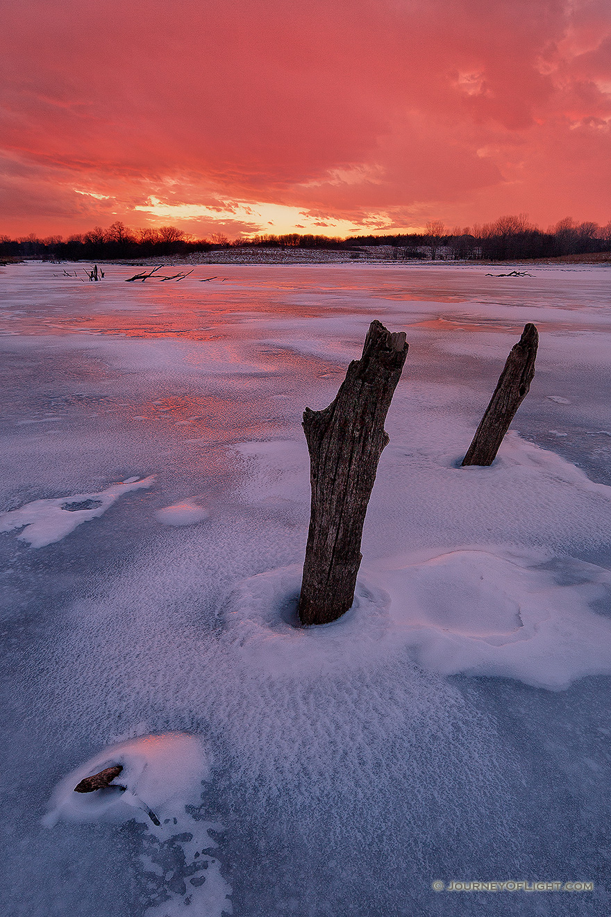 On a chilly February evening the setting sun illuminates the clouds in the western sky with a dazzling crimson color. - Nebraska Picture