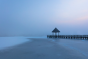 A scenic landscape photograph of fog over a frozen lake and a dock at Walnut Creek, Nebraska. - Nebraska Photograph