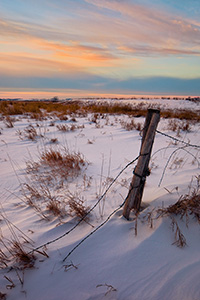 Barbed wire emergences from the snow to attach to a forgotten fence post at Jack Sinn Wildlife Management Area. - Nebraska Photograph