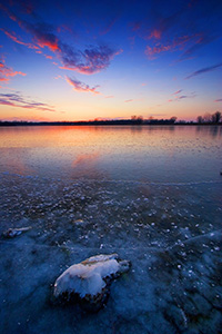 This photograph was captured in the dead of winter, when the old Missouri River oxbow at DeSoto National Wildlife Refuge transforms into a reflective sheet of ice with a single rock still visible. - Nebraska Photograph