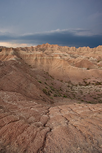 As a storm passes over Badlands National Park in South Dakota, dark clouds contrast with the desolate landscape. - South Dakota Photograph