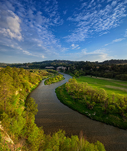 The Niobrara river, snakes through a lush green valley on a beautiful spring morning. A cool breeze blew gently as the sun rose in the east illuminating the clouds in the sky. - Nebraska Landscape Photograph