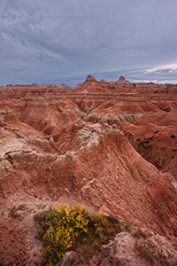 Afternoon storm clouds gather over the rock formations deep in Badlands National Park as a waning moon gentle descends behind. - South Dakota Photograph