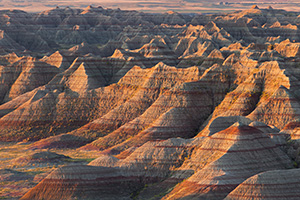 The warm light of the recently risen sun illuminates the Badlands of South Dakota in Badlands National Park. - South Dakota Photograph