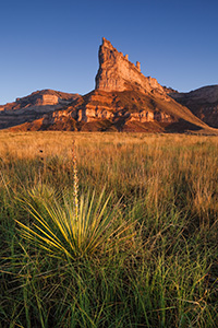 Scotts Bluff National Monument in western Nebraska.  Towering eight hundred feet above the North Platte River, Scotts Bluff has been a natural landmark for many peoples, and it served as the path marker for those on the Oregon, California, Mormon, and Pony Express Trails.  Scotts Bluff National Monument preserves 3,000 acres of unusual land formations which rise over the otherwise flat prairieland below. - Nebraska Photograph