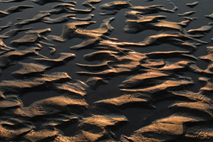 Capturing a photograph of a nature abstract, sand and water collide and intermingle to create interesting patterns along the banks of the Platte River in Eastern Nebraska. - Nebraska Photograph