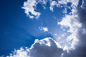 Sunbeams radiate from behind a cloud in the deep azure sky at Valentine National Wildlife Refuge, Nebraska. - Nebraska Photograph