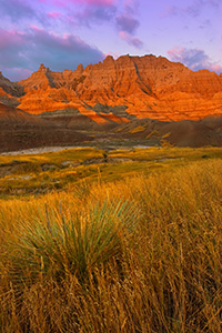 The morning sun emits a glow that radiates orange off the unusual formations in the Badlands National Park. - South Dakota Photograph