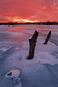 On a chilly February evening the setting sun illuminates the clouds in the western sky with a dazzling crimson color. - Nebraska Photograph