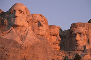 The warm sunrise light illuminates the faces with a reddish hue. - South Dakota Photograph