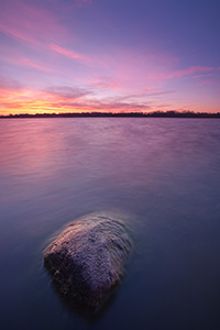 On a late Autumn morning, clouds on the horizon of Stagecoach Lake in Lancaster County, Nebraska are illuminated with bright yellows and reds. - Nebraska Photograph