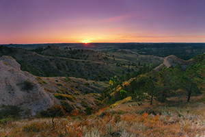 On an early fall morning, the rising sun shines brightly across Chadron State Park, in western Nebraska. - Nebraska Photograph