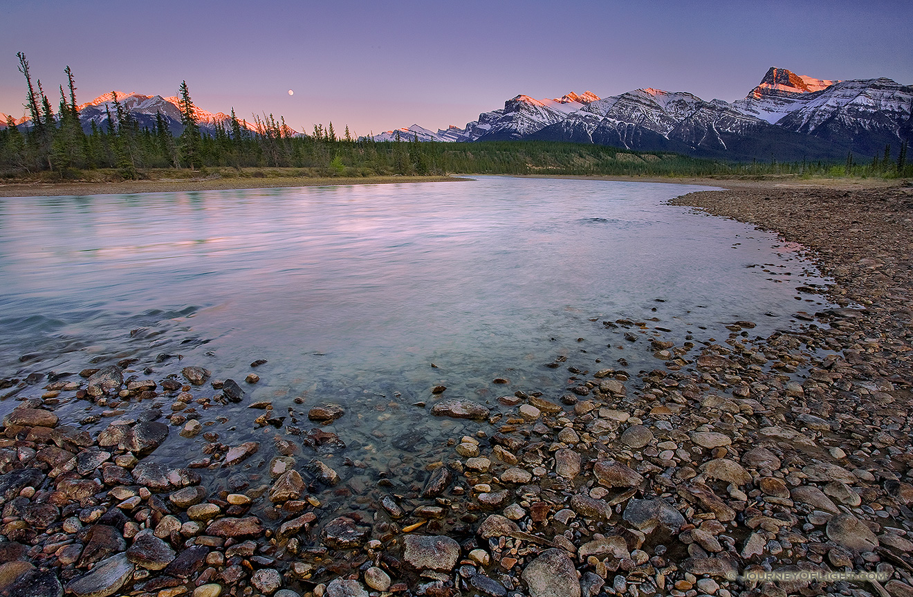 A nearly full moon rises above the Canadian Rockies while the last glow of the sun reflects off of the moutain tops. - Canada Picture