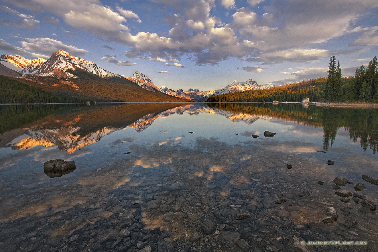 Clouds float lazily down the water as the last light hits at Maligne Lake located in Jasper National Park. - Canada Picture