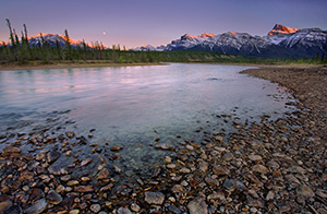 A nearly full moon rises above the Canadian Rockies while the last glow of the sun reflects off of the moutain tops. - Canada Photograph