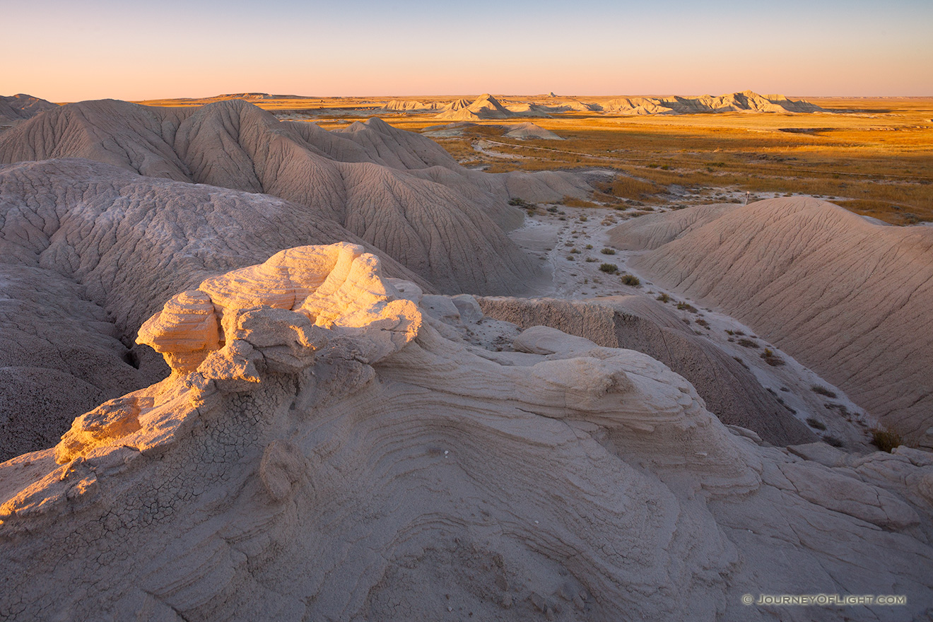 As the sun sets warm sunlight bathes parts of Toadstool Geologic Park in warm hues. - Toadstool Geologic Park Picture