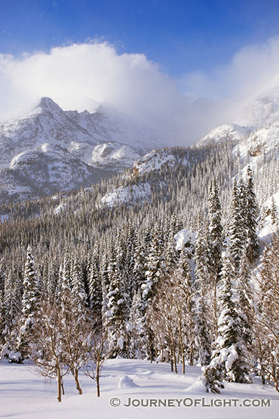 On the trail to Dream Lake, Long's Peak is obscured, encased in blowing snow and clouds in Rocky Mountain National Park, Colorado.