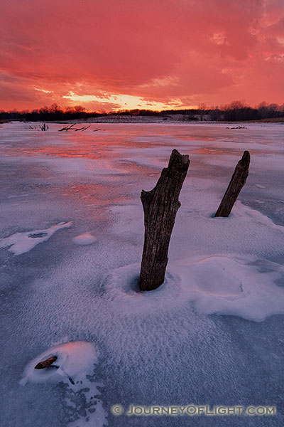 On a chilly February evening the setting sun illuminates the clouds in the western sky with a dazzling crimson color.