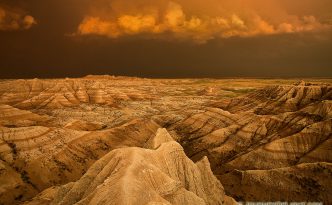Facing east, the sky was nearly pitch black shrouded by the fierce storm that had just passed through. As the sun dipped below the horizon the last rays hit the trailing storm clouds and the ambient warm light lit up the valley across the Badlands in South Dakota.