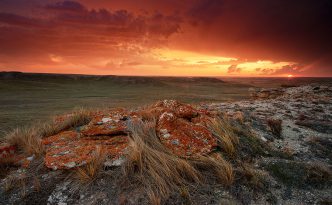 Evening descended and dark clouds moved slowly across the sky to the north on a cool, spring evening at Agate Fossil Beds National Monument in far western Nebraska. As the sun set in the west, it's orange glow illuminated the scene with fiery oranges and reds, briefly before being lost below the horizon.