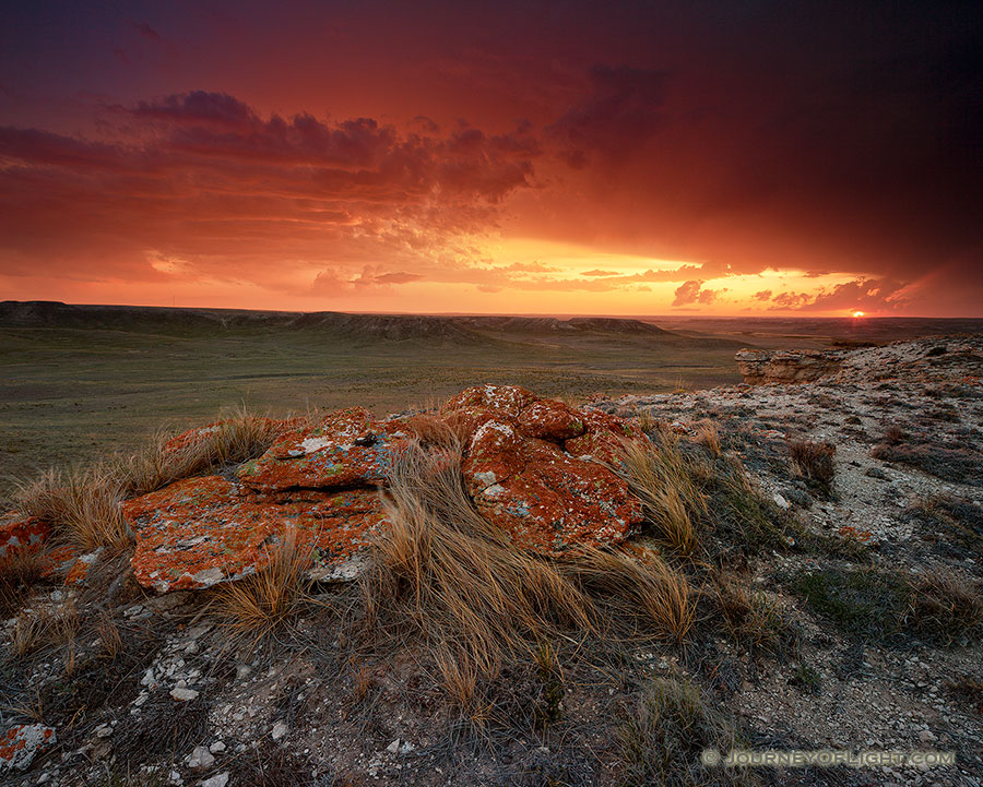 Evening descended and dark clouds moved slowly across the sky to the north on a cool, spring evening at Agate Fossil Beds National Monument in far western Nebraska. As the sun set in the west, it's orange glow illuminated the scene with fiery oranges and reds, briefly before being lost below the horizon.