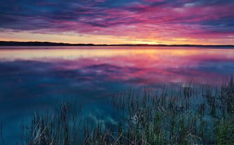 A small lake nestled in the Sandhills reflects the rising sun on a cool spring morning.