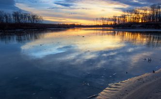 Pawprints from a racoon are illuminated on the shore as the sun rises over the Missouri River at Ponca State Park in northeastern Nebraska.