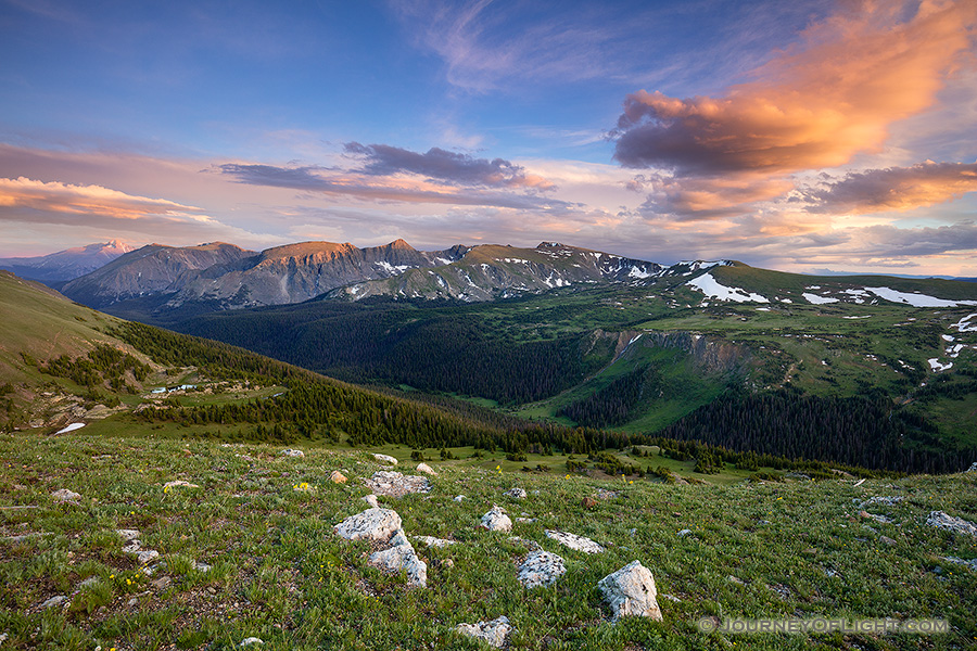 Clouds gather above the tops of the mountains in Rocky Mountain National Park as the last warm glow of sunset grazes the peaks.